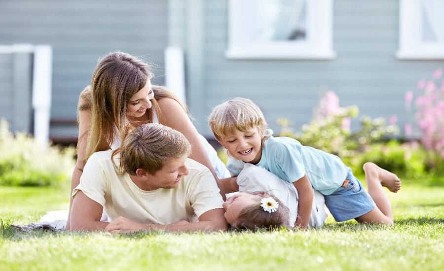 Children playing with parents in the garden of their insured home - Blue Lion Insurance Advisors
