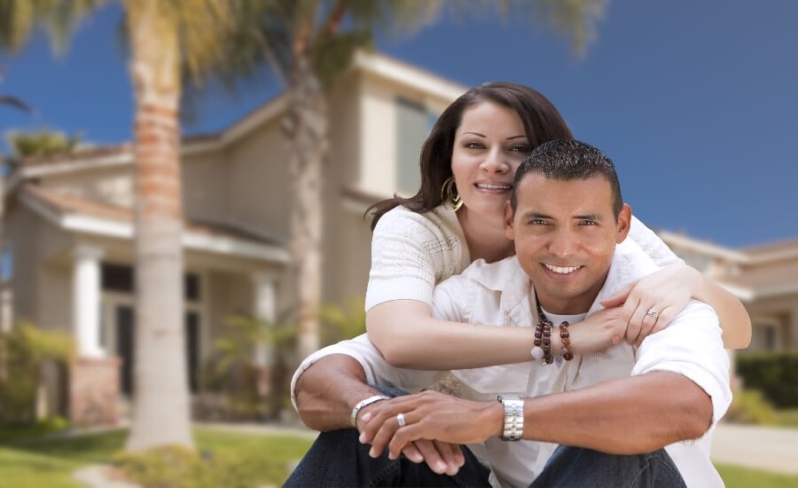 Young Happy Hispanic Young Couple in Front of Their New Home - Blue Lion Insurance Advisors